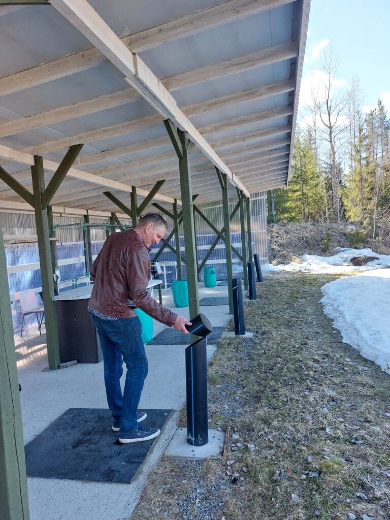 mies kokeilee katoksen alla ammuntaan liittyviä laitteita